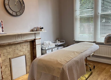 Serene therapy room at The London Road Clinic, Newark-on-Trent, England, featuring cozy fireplace and treatment bed.
