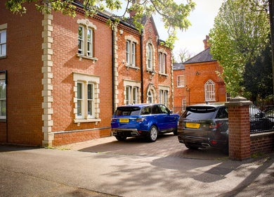The London Road Clinic's charming brick exterior in Newark-on-Trent, England, GB with cars parked outside.