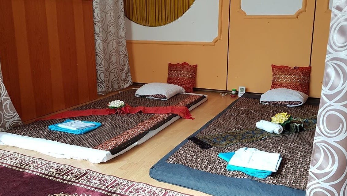 Traditional Thai massage setup at Urai Thai Massage, Budapest, HU with mats, pillows, and decorative flowers.