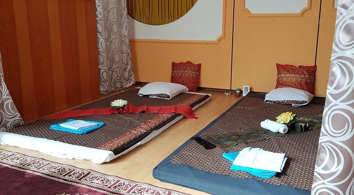 Traditional Thai massage setup at Urai Thai Massage, Budapest, HU with mats, pillows, and decorative flowers.