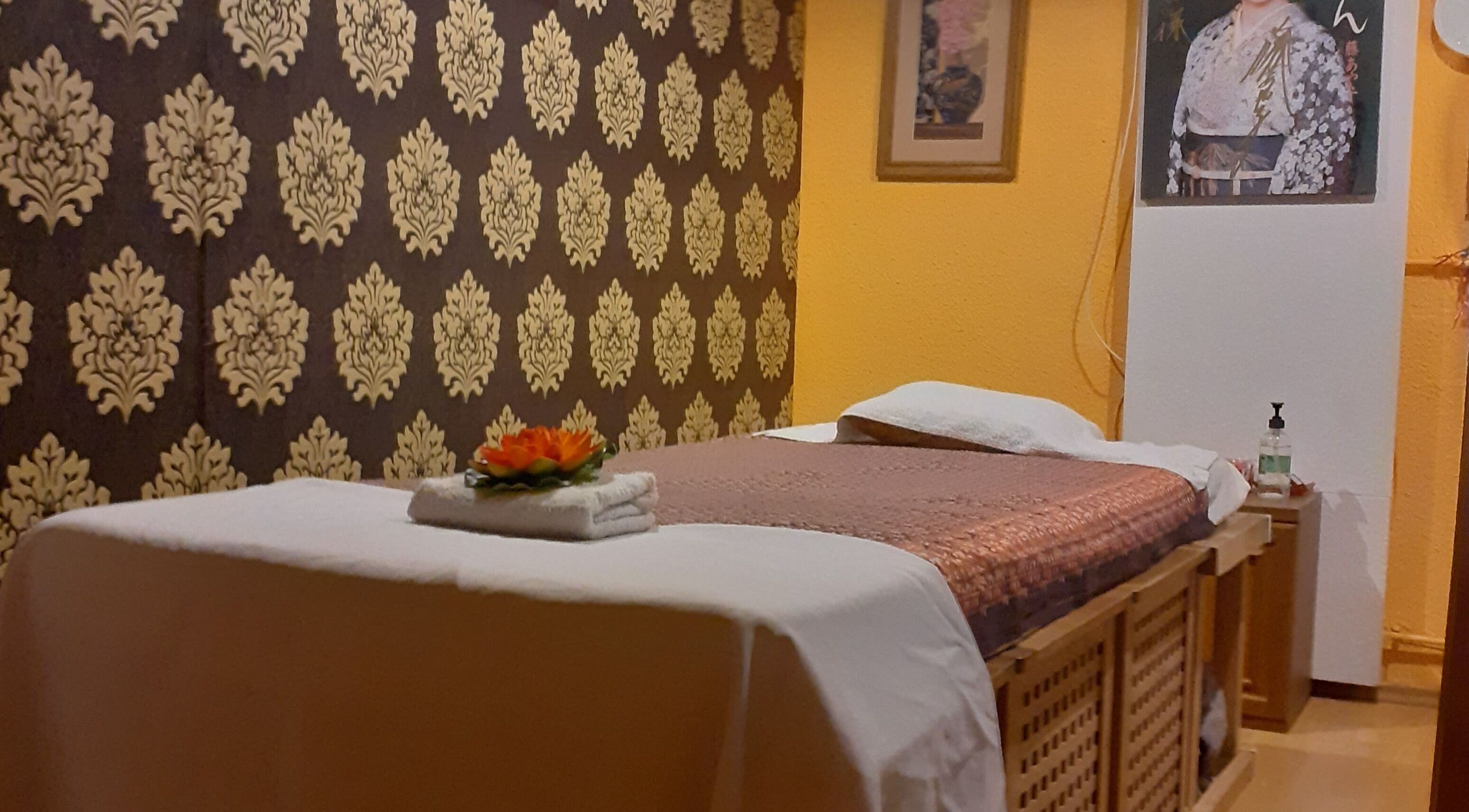 Serene massage room at Urai Thai Massage, Budapest, HU with a beautifully decorated bed and soft lighting.