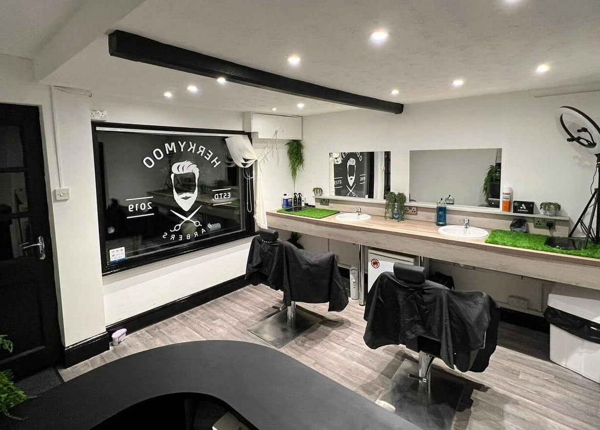 Modern barber interior at Herkymoo Herstmonceux in Herstmonceux, England, GB with sleek black chairs and large mirrors.