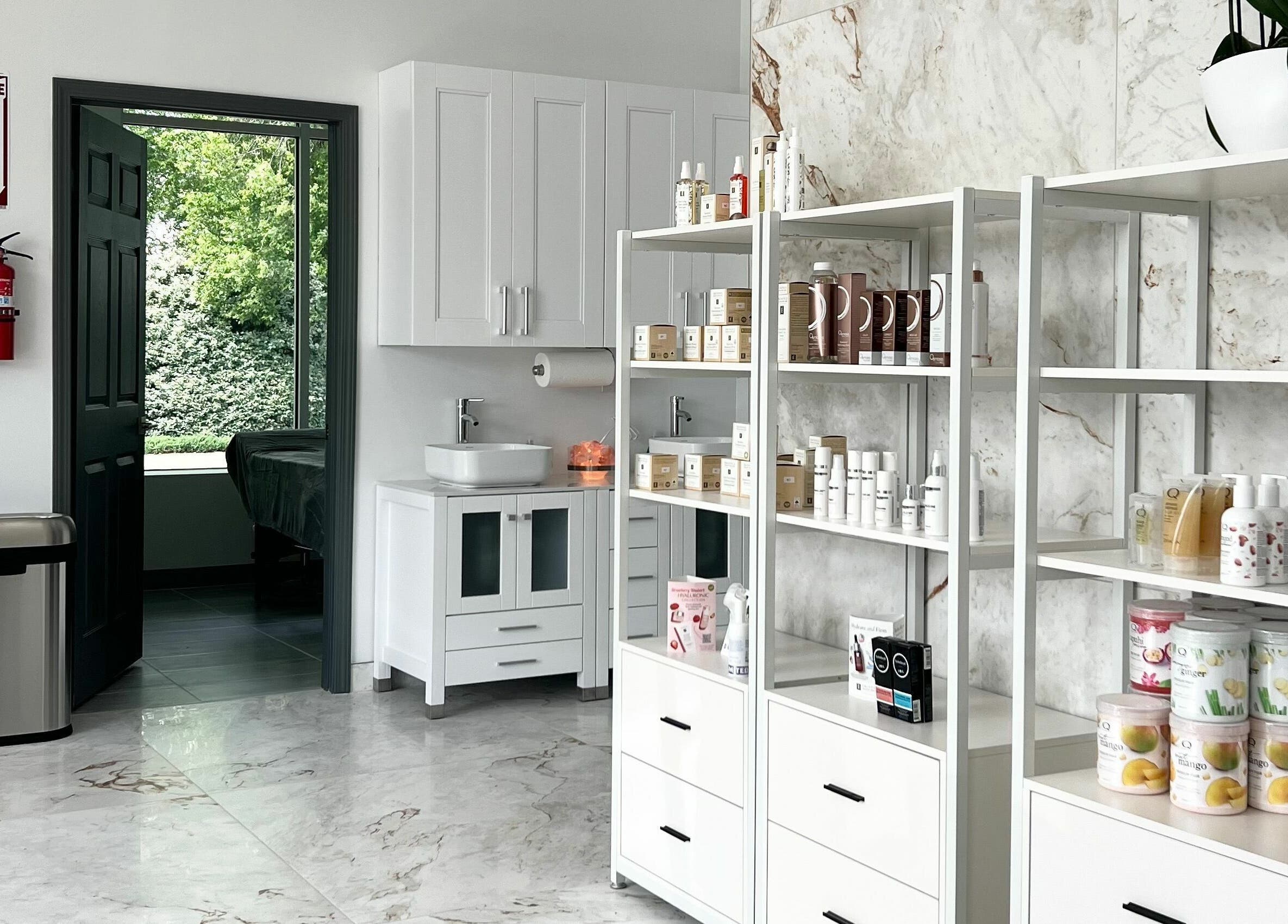 Bright interior of Vogue Lashes and Spa in Virginia Beach, showcasing products on sleek white shelves.