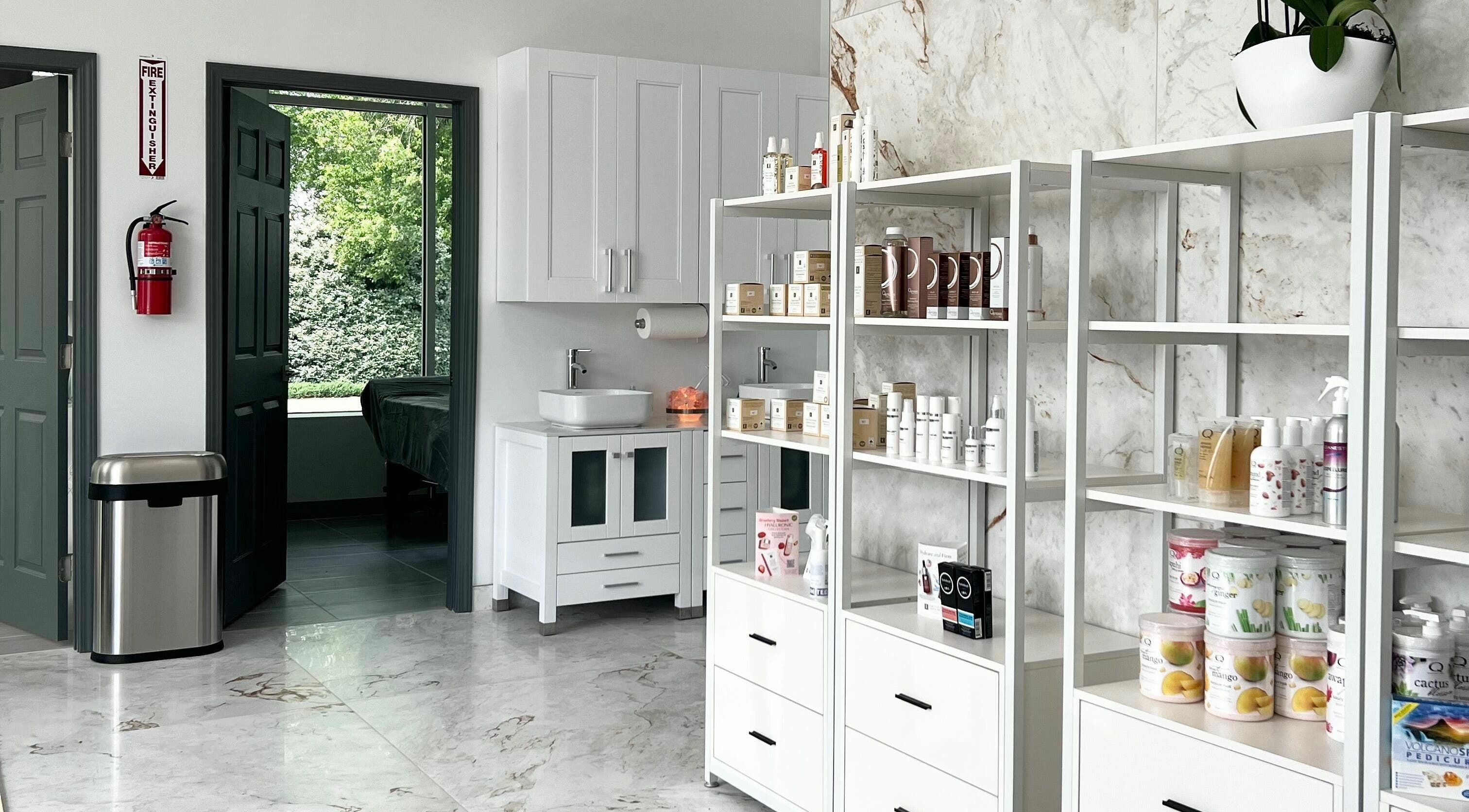 Bright interior of Vogue Lashes and Spa in Virginia Beach, showcasing products on sleek white shelves.