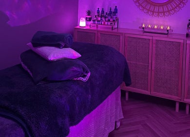 Relaxing massage room at The Holistic Haven, Swindon, England, GB, with soft purple lighting and cozy decor.
