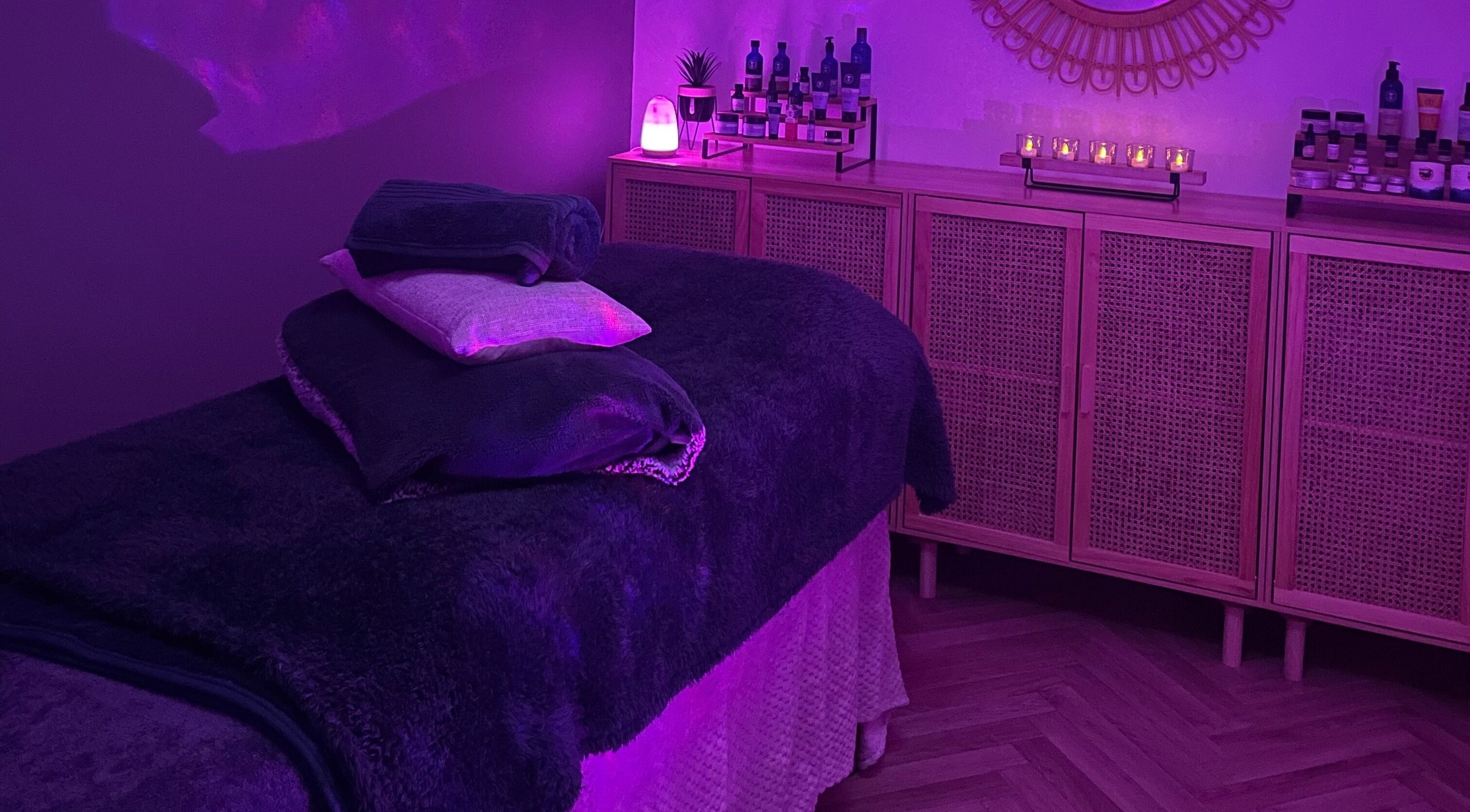 Relaxing massage room at The Holistic Haven, Swindon, England, GB, with soft purple lighting and cozy decor.