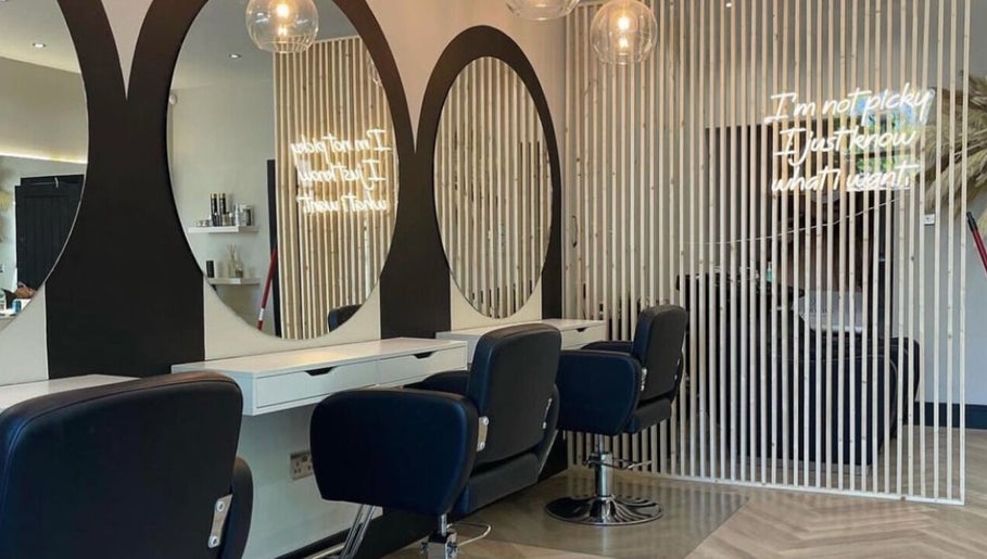 Stylish salon styling area at By.CharleyHulme (Hair) in Leeds, England, GB with sleek black chairs and large round mirrors.