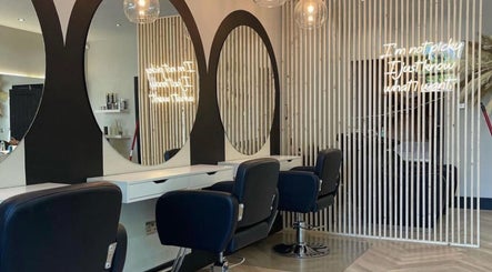 Stylish salon styling area at By.CharleyHulme (Hair) in Leeds, England, GB with sleek black chairs and large round mirrors.