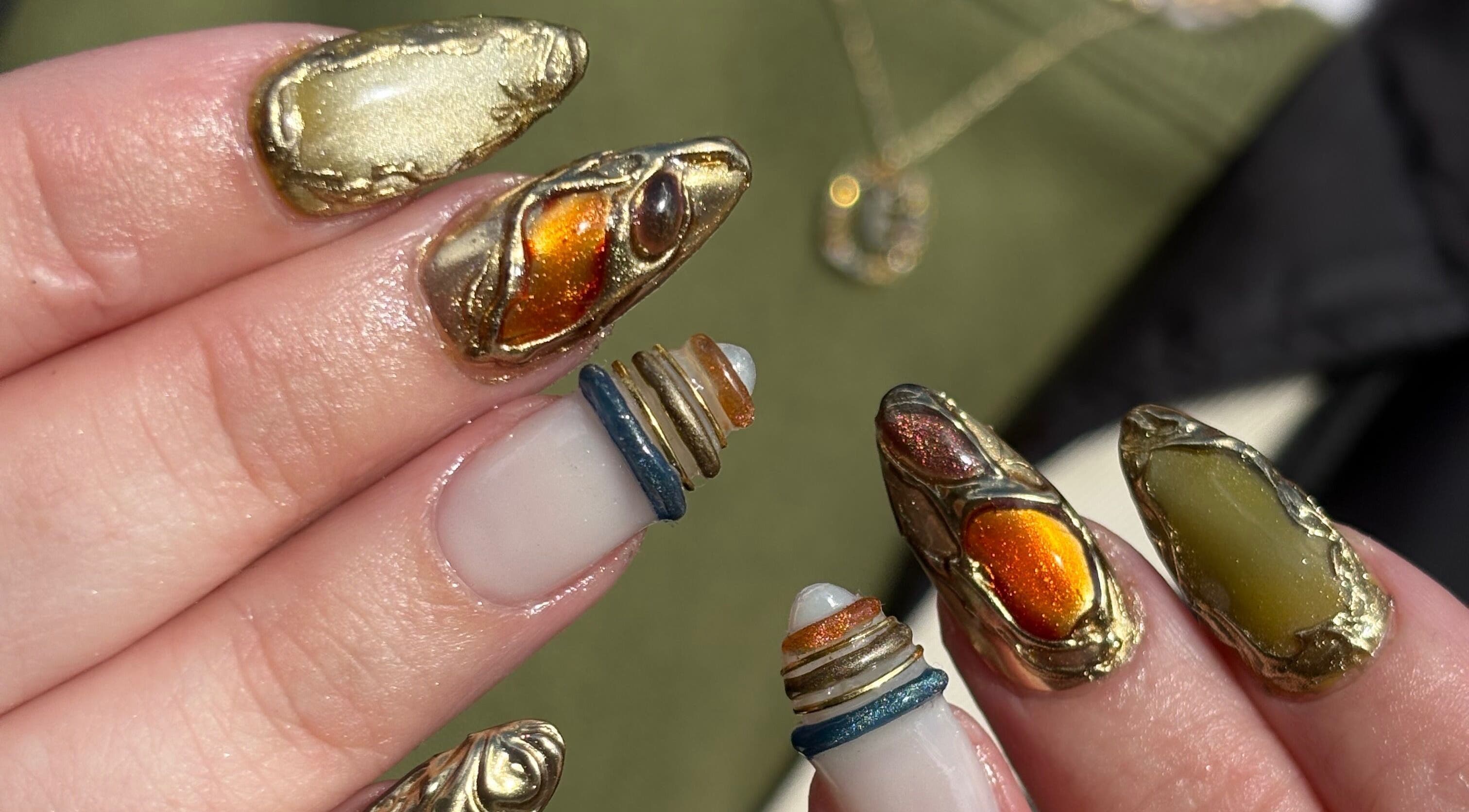 Intricate golden nail art byphoeb in Cardiff, Wales, GB, featuring metallic accents and bold designs.