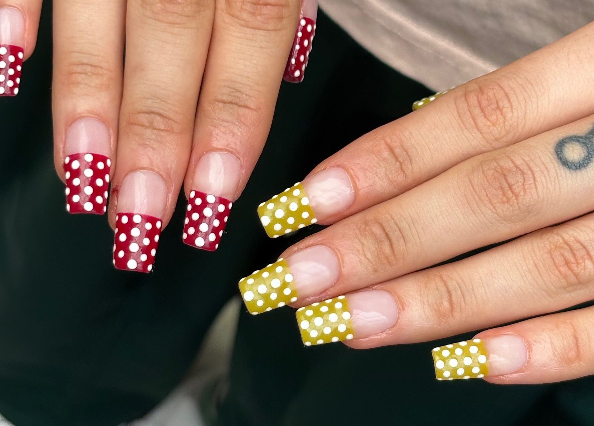Stylish polka dot nail art in red and yellow at byphoeb, Cardiff, Wales, GB, showcasing creative nail designs.
