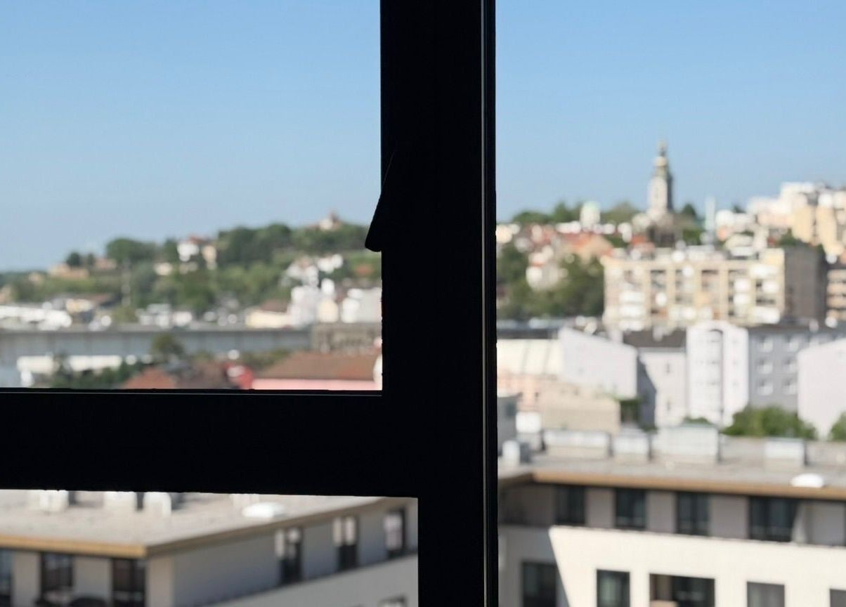 Pogled kroz prozor AMP - studio za nokte na Beograd, RS s urbanim pejsažem.