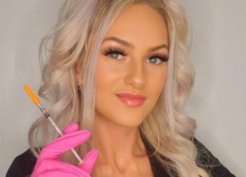 Professional injector smiling at GCI Advanced Aesthetics, Aberdeen, Scotland, GB, holding a syringe with care.