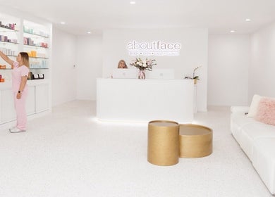 Modern reception area at About Face, Taree, New South Wales, AU, showcasing sleek white design and product display.