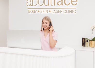 Reception desk at About Face, Taree, New South Wales, AU with staff in pink uniform on phone.