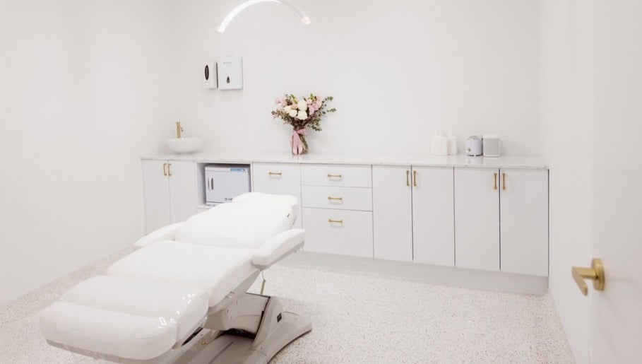 Elegant treatment room at About Face, Taree, New South Wales, AU, featuring a plush white bed and soft lighting.