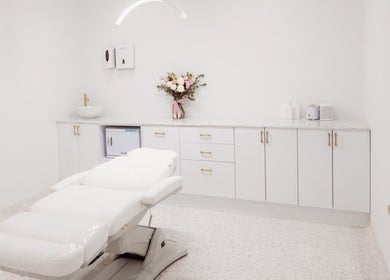 Elegant treatment room at About Face, Taree, New South Wales, AU, featuring a plush white bed and soft lighting.