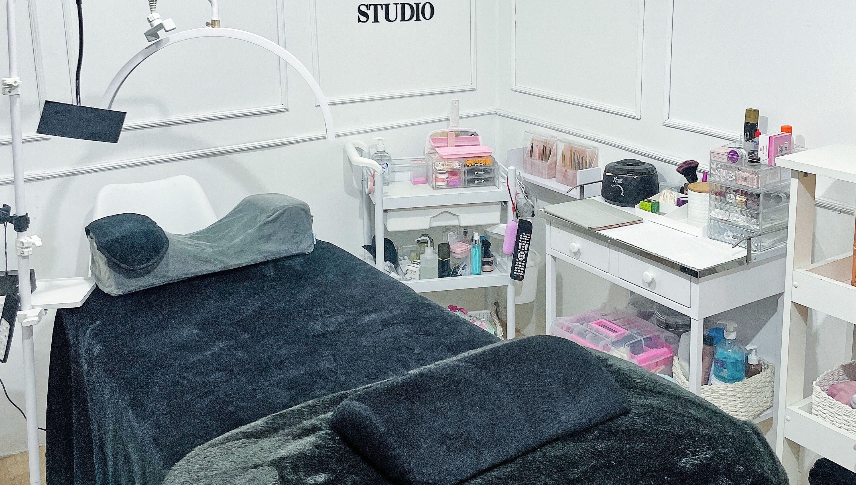 Sala de tratamiento en MO Studio, Callao, con camilla negra y productos de belleza organizados.