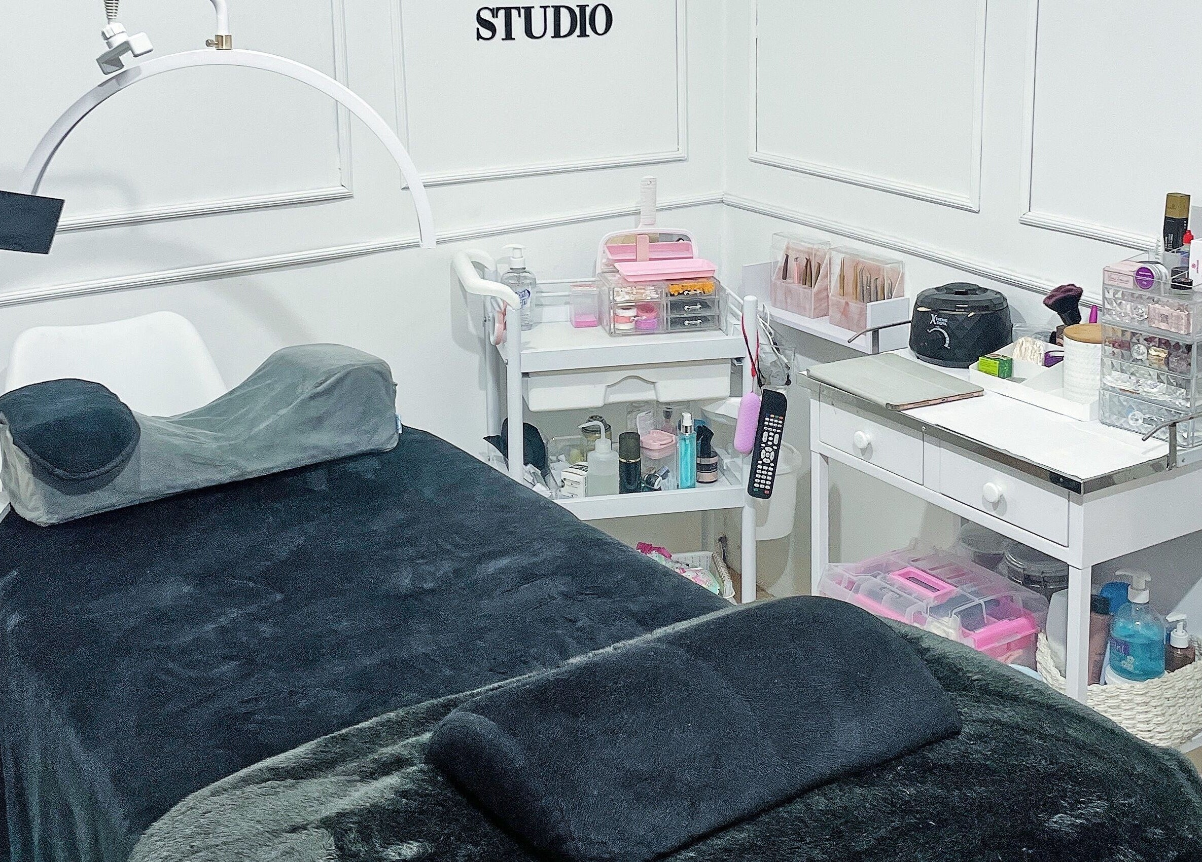 Sala de tratamiento en MO Studio, Callao, con camilla negra y productos de belleza organizados.