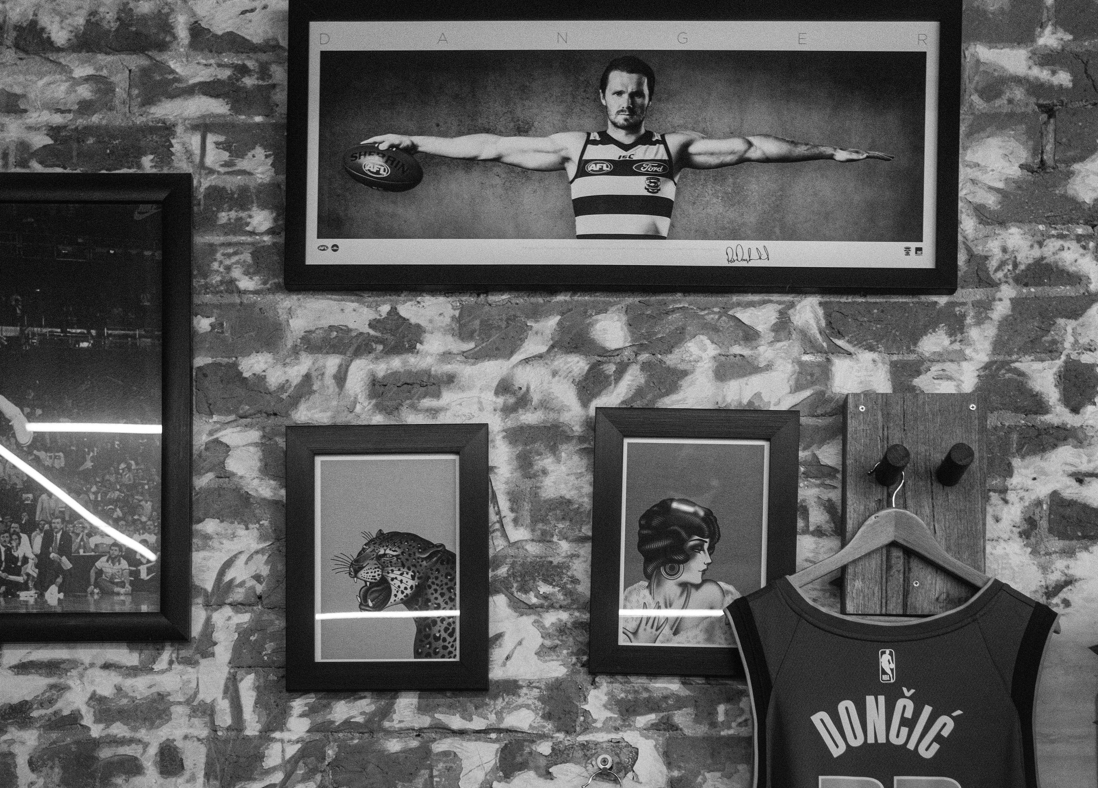 Stylish wall decor at Lighthouse Barbers in Melbourne, Victoria, AU showcasing framed art and a jersey.