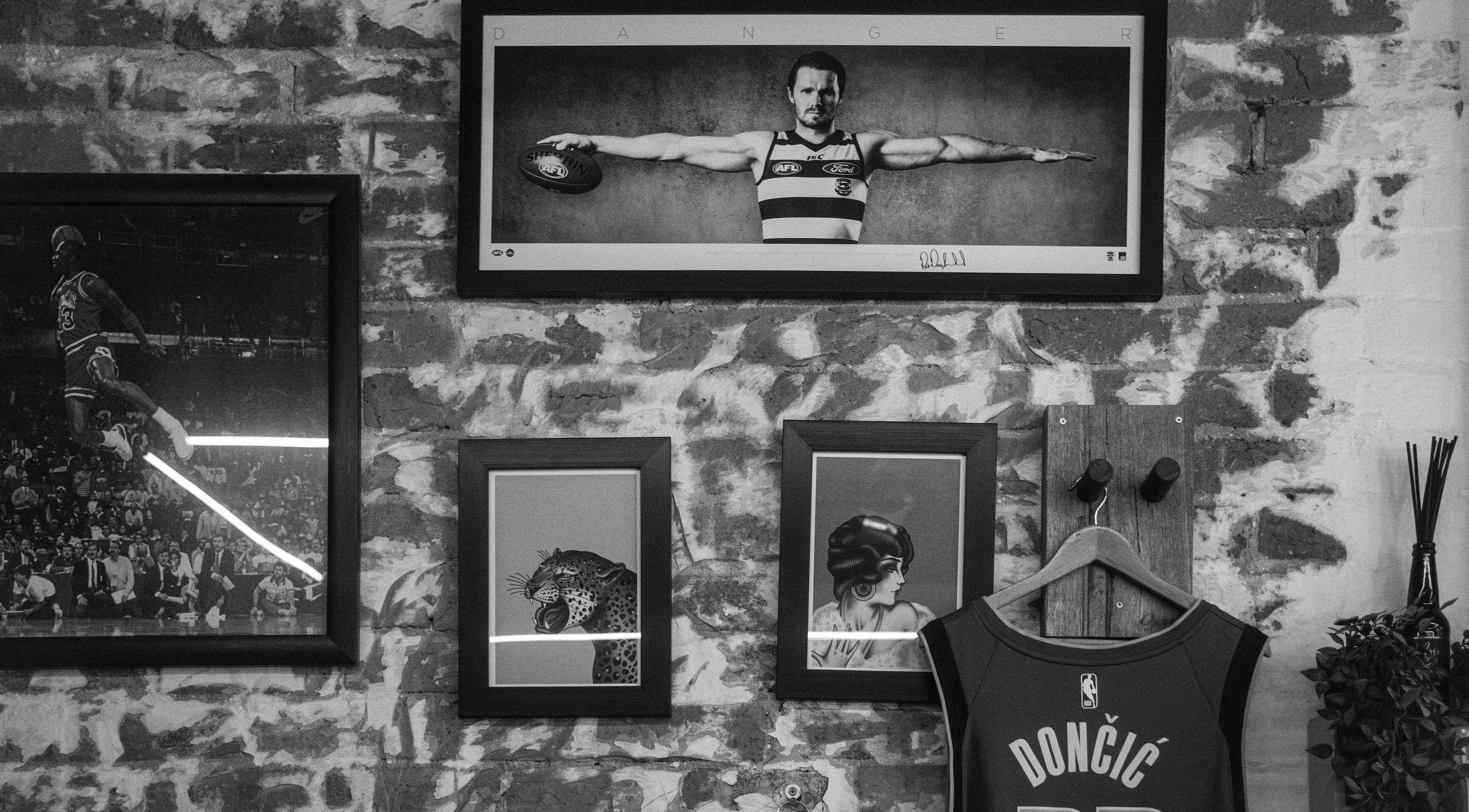 Stylish wall decor at Lighthouse Barbers in Melbourne, Victoria, AU showcasing framed art and a jersey.