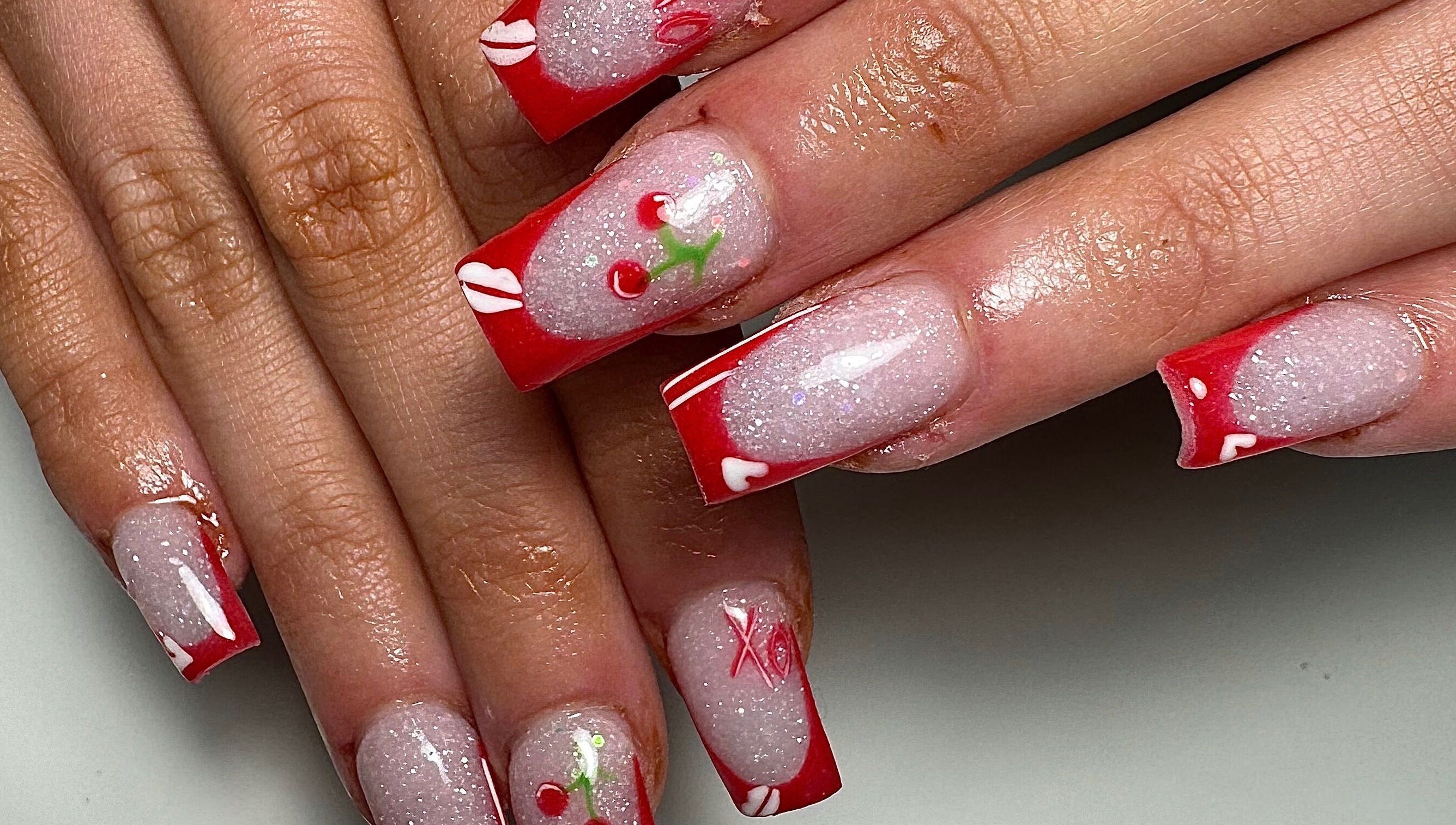 Cherry-themed nail art at Gloxy Nails, Banbridge, Northern Ireland, GB, showcasing red and glitter designs.