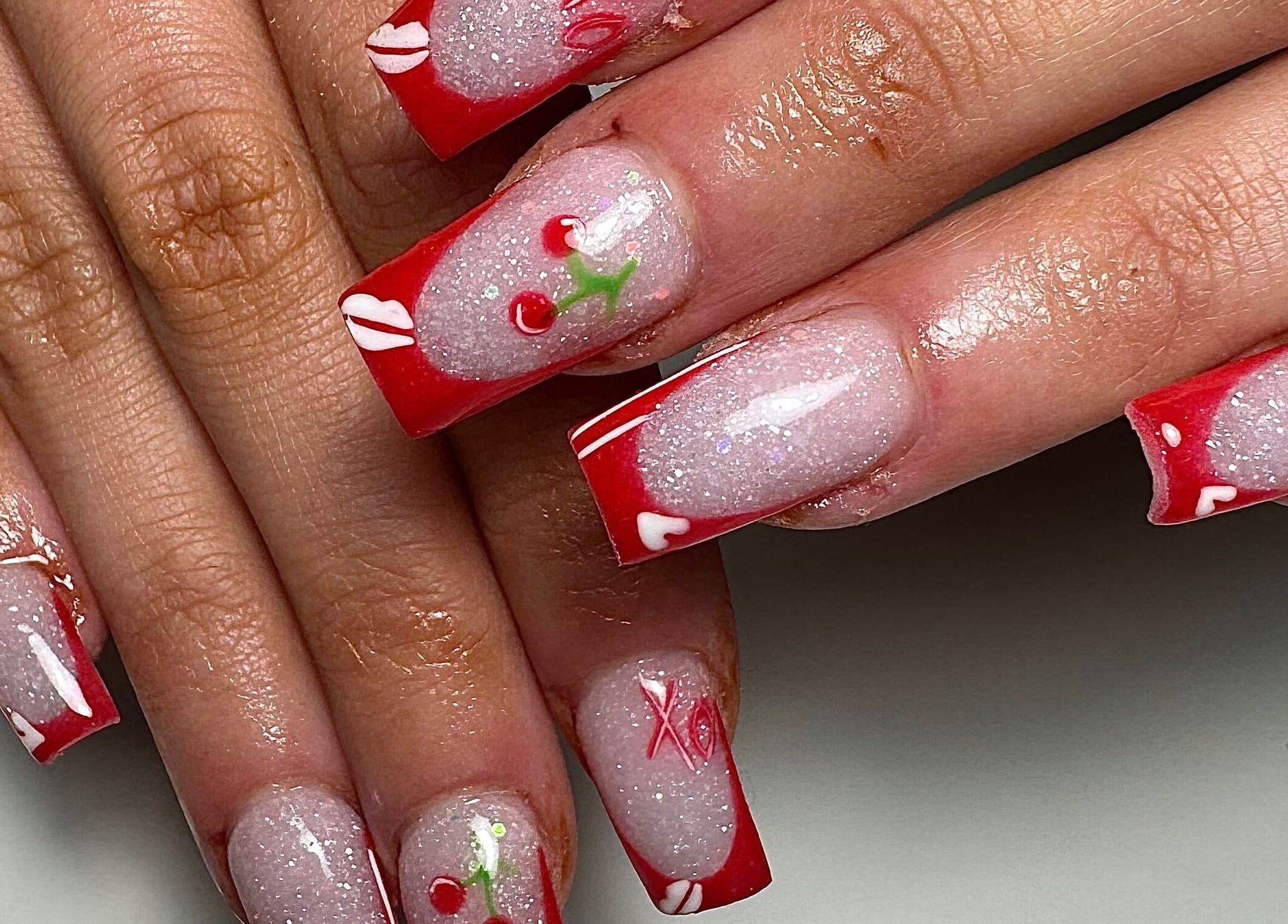 Cherry-themed nail art at Gloxy Nails, Banbridge, Northern Ireland, GB, showcasing red and glitter designs.