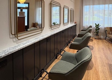 The Vanity salon in Turvey Park, New South Wales, AU features stylish chairs and elegant mirrors along a sleek bar.