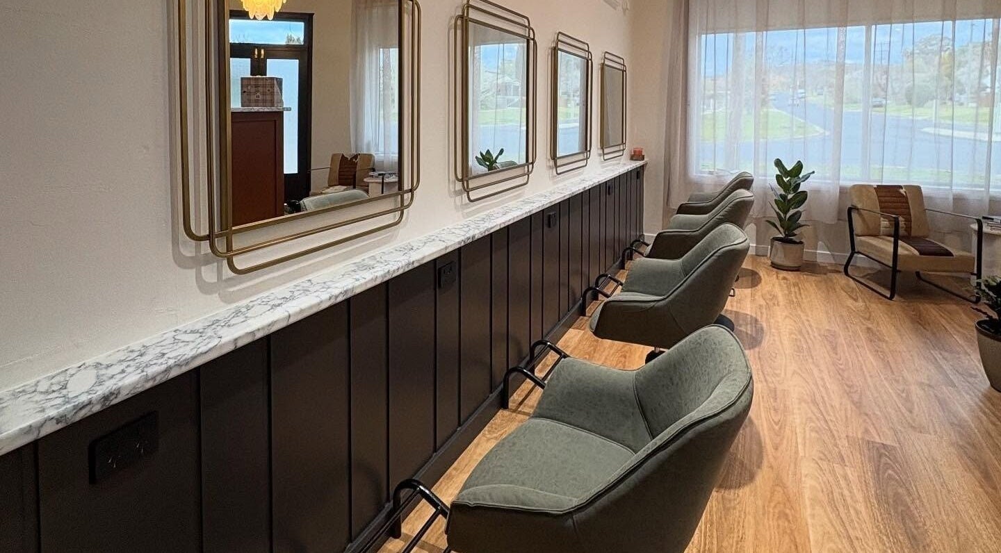 The Vanity salon in Turvey Park, New South Wales, AU features stylish chairs and elegant mirrors along a sleek bar.