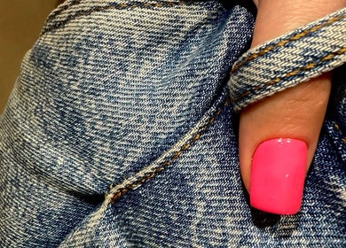 Bright pink nail art showcased at SORSIA, Bournemouth, England, GB with denim background.