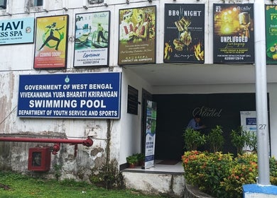 Entrance of Meghavi Wellness Spa | The Stadel, Kolkata, showcasing various event posters and greenery.
