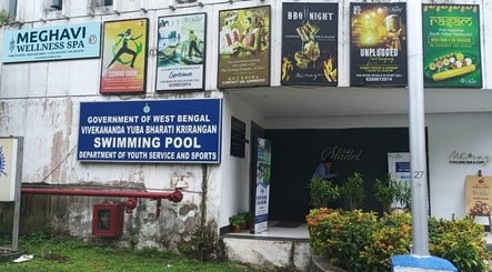Entrance of Meghavi Wellness Spa | The Stadel, Kolkata, showcasing various event posters and greenery.