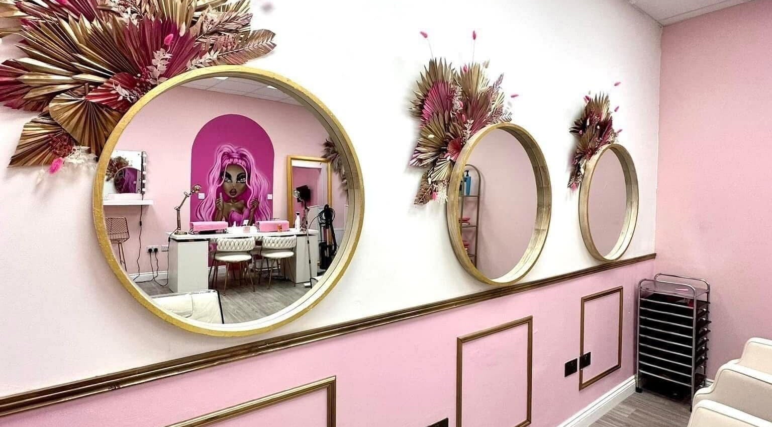 Stylish interior of Hair By Ellie in Sunderland, England, with decorative mirrors and vibrant pink accents.
