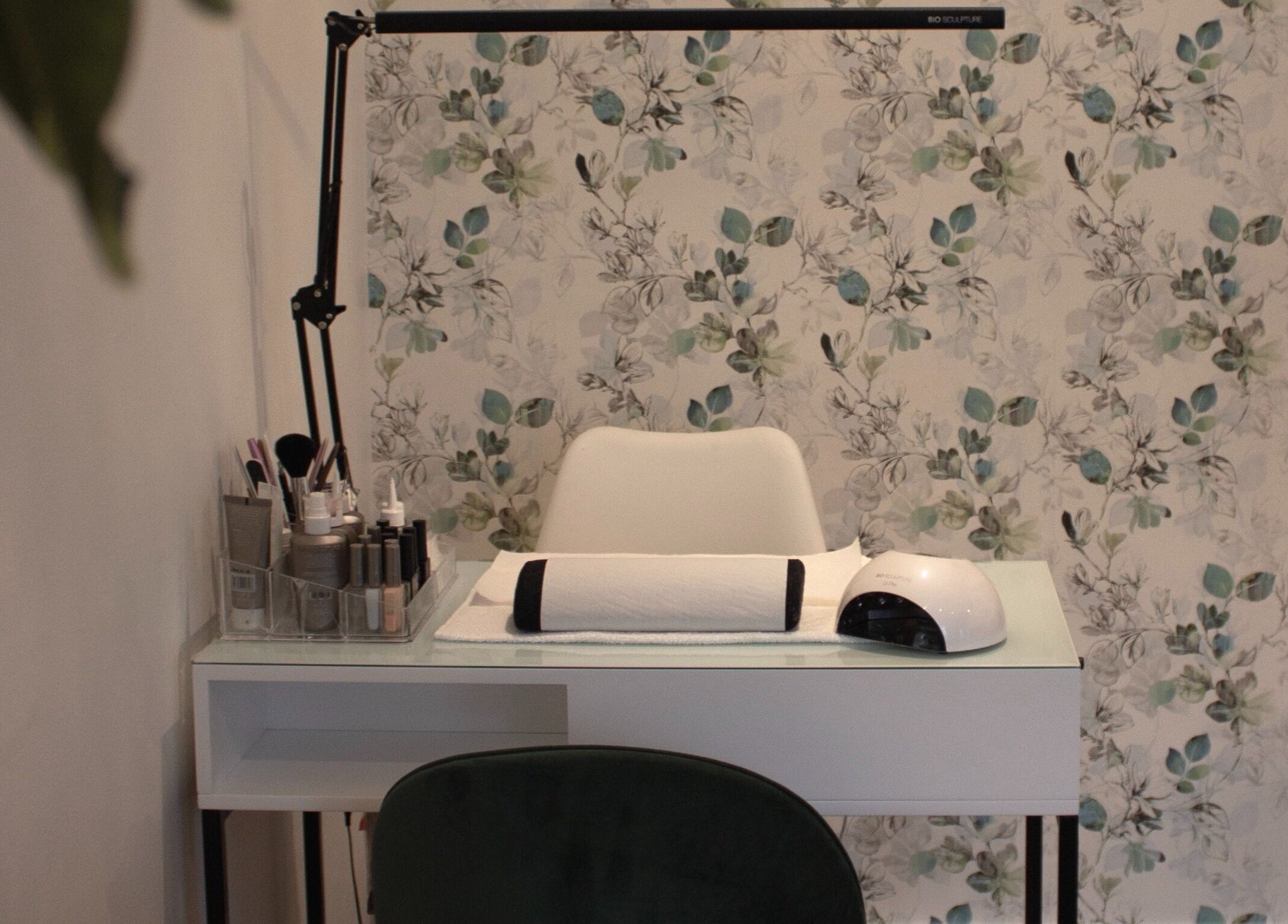 Manicure station at The Skin Firm in Cape Town, Western Cape, ZA featuring intricate floral wallpaper.