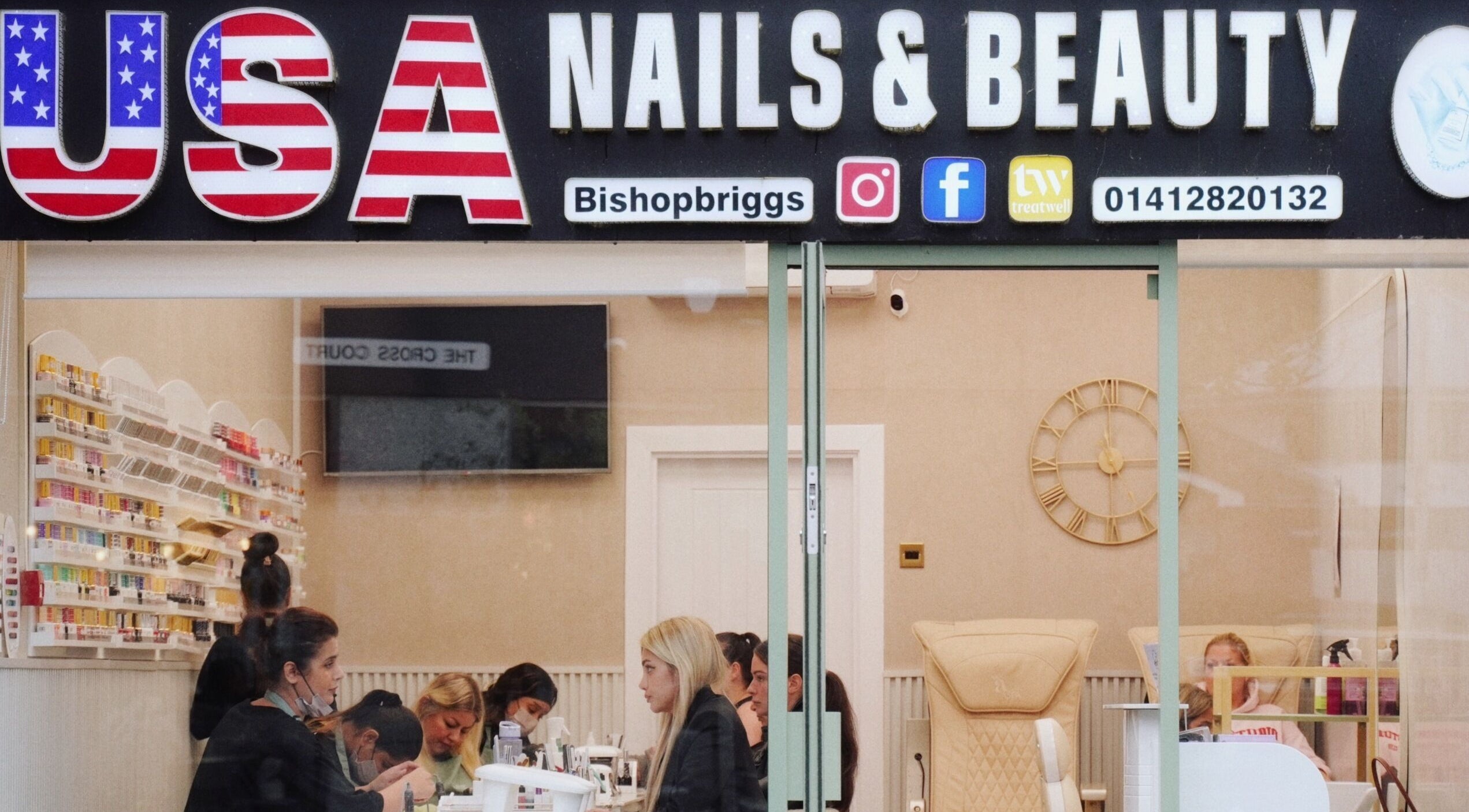 Inside USA Nail and Beauty in Bishopbriggs, Scotland, GB, showcasing vibrant nail polish shelves and busy staff.