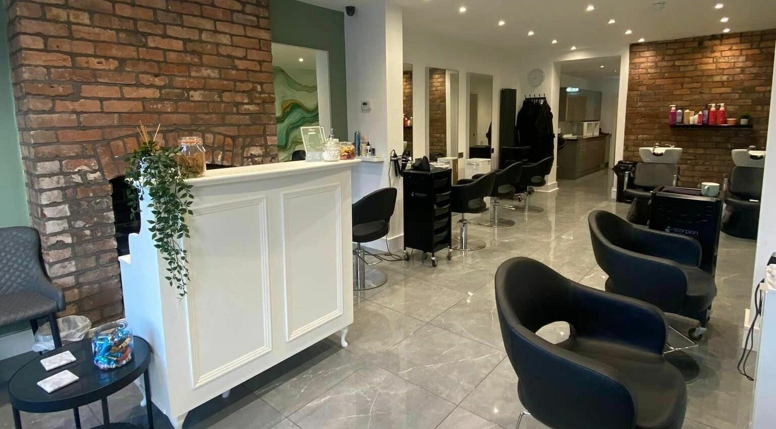 Interior of Muse Hair & Beauty in Chadderton, England, GB with modern chairs and exposed brick walls.