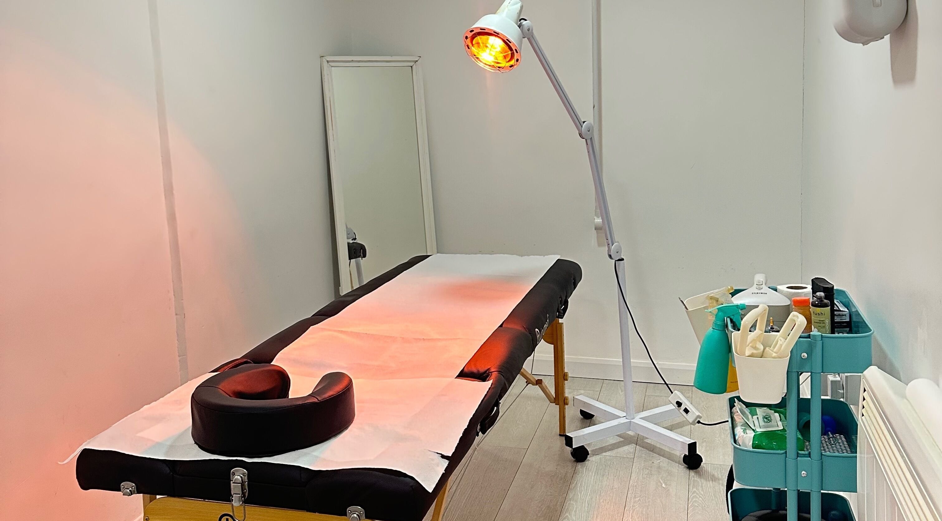 Therapy room at Cupping Clinic, London, England, GB featuring massage table and warm lighting setup.
