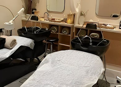 Elegant salon interior at SOLO, Ajman, Ajman, AE with two stylish black wash stations and cozy white linens.