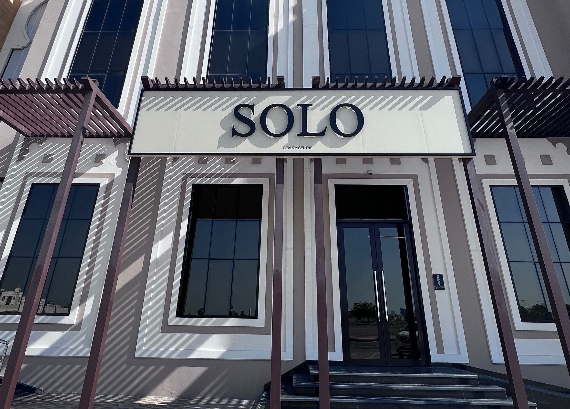 Elegant entrance of SOLO beauty center in Ajman, Ajman, AE with modern architecture and large windows.