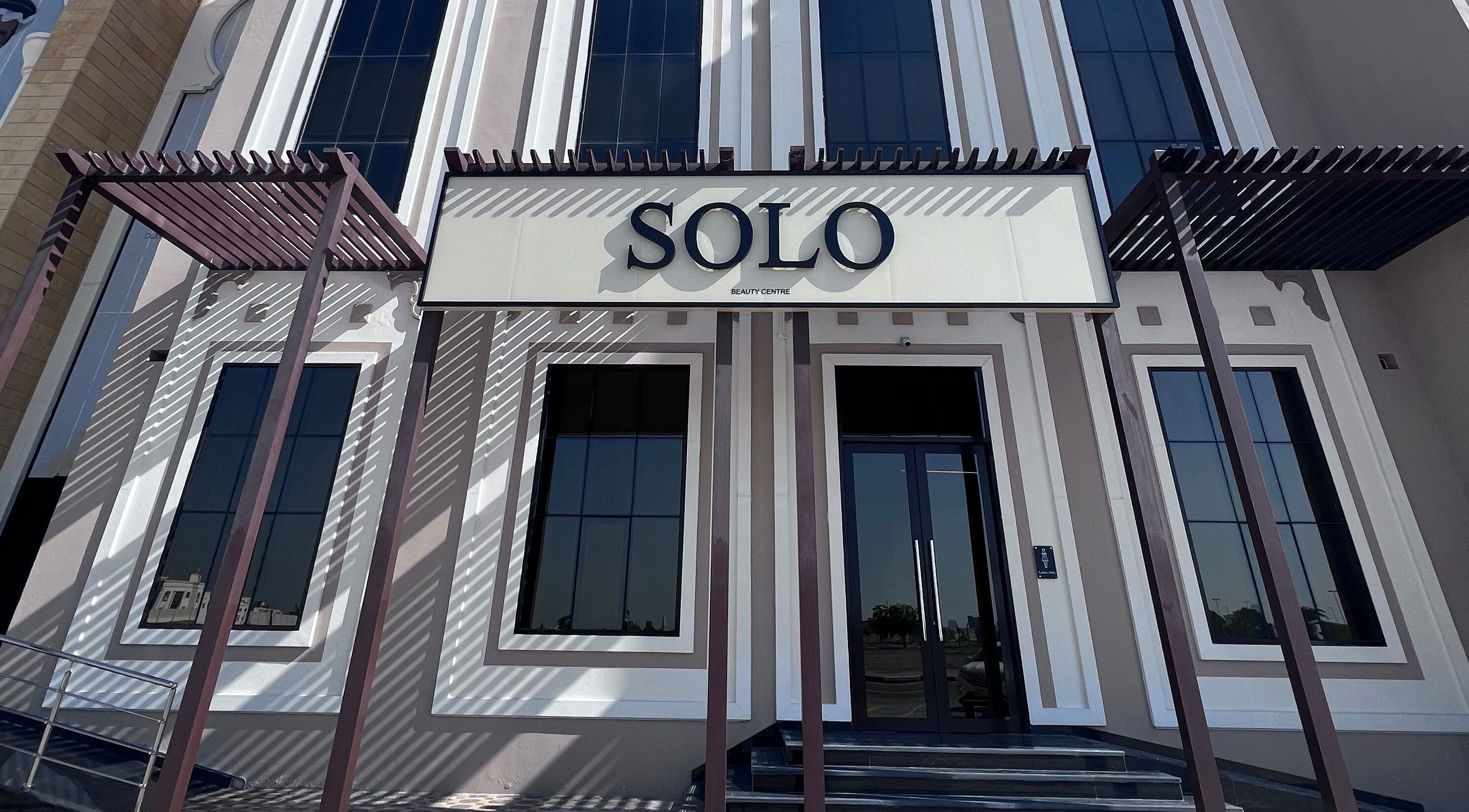 Elegant entrance of SOLO beauty center in Ajman, Ajman, AE with modern architecture and large windows.