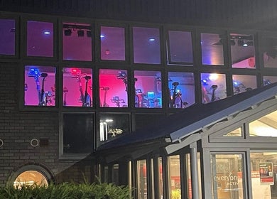 Illuminated spin studio at Farnborough Sports Massage, Farnborough, England, GB, showing indoor bikes through large windows.