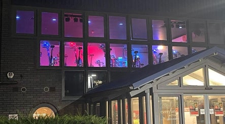 Illuminated spin studio at Farnborough Sports Massage, Farnborough, England, GB, showing indoor bikes through large windows.