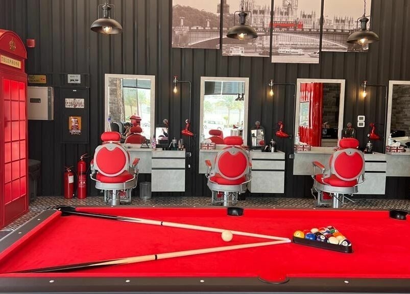 Interior of London Base Barbershop - Business Bay in Dubai, AE featuring red chairs, mirrors, and a pool table.