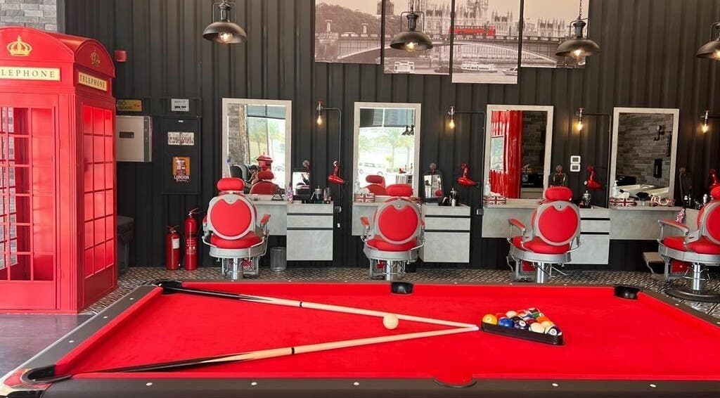 Interior of London Base Barbershop - Business Bay in Dubai, AE featuring red chairs, mirrors, and a pool table.