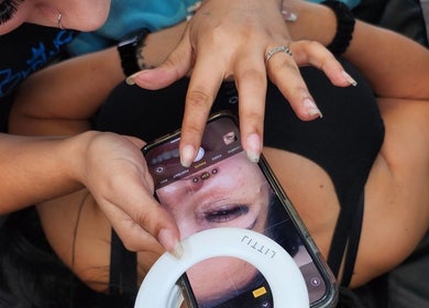 Lyla Brows & Beauty specialist examines brows at Deerfield Beach, Florida, US with a smartphone close-up.