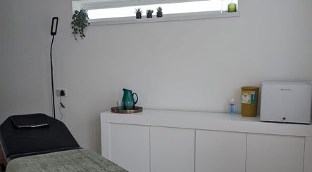 Calm treatment room at SALO Aesthetics in Plymouth, England, GB, featuring a bed and decor.