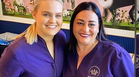 Two smiling staff members at Beauty On Queen, Ashmore, Queensland, AU, in matching uniforms.