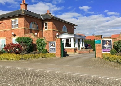Bare Beauty in Strensall, England, showcases a charming brick exterior surrounded by manicured shrubs.