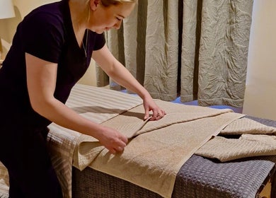 Team member preparing massage table at Bare Beauty, Strensall, England, GB. Cozy ambiance and professional care.