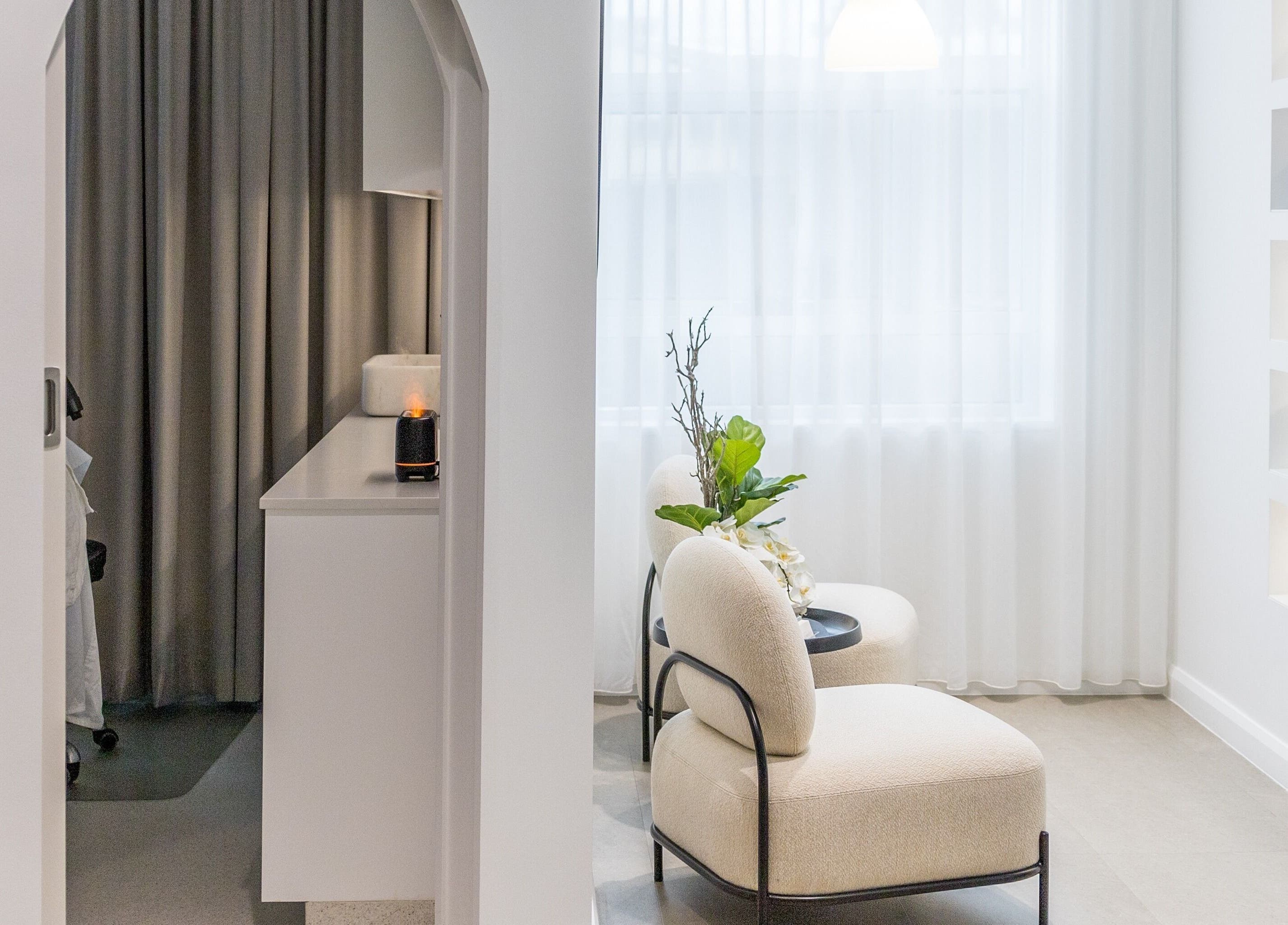 Relaxing lounge area at Simply Luminous Skin, Wentworth Point, New South Wales, AU with elegant chairs and soft lighting.