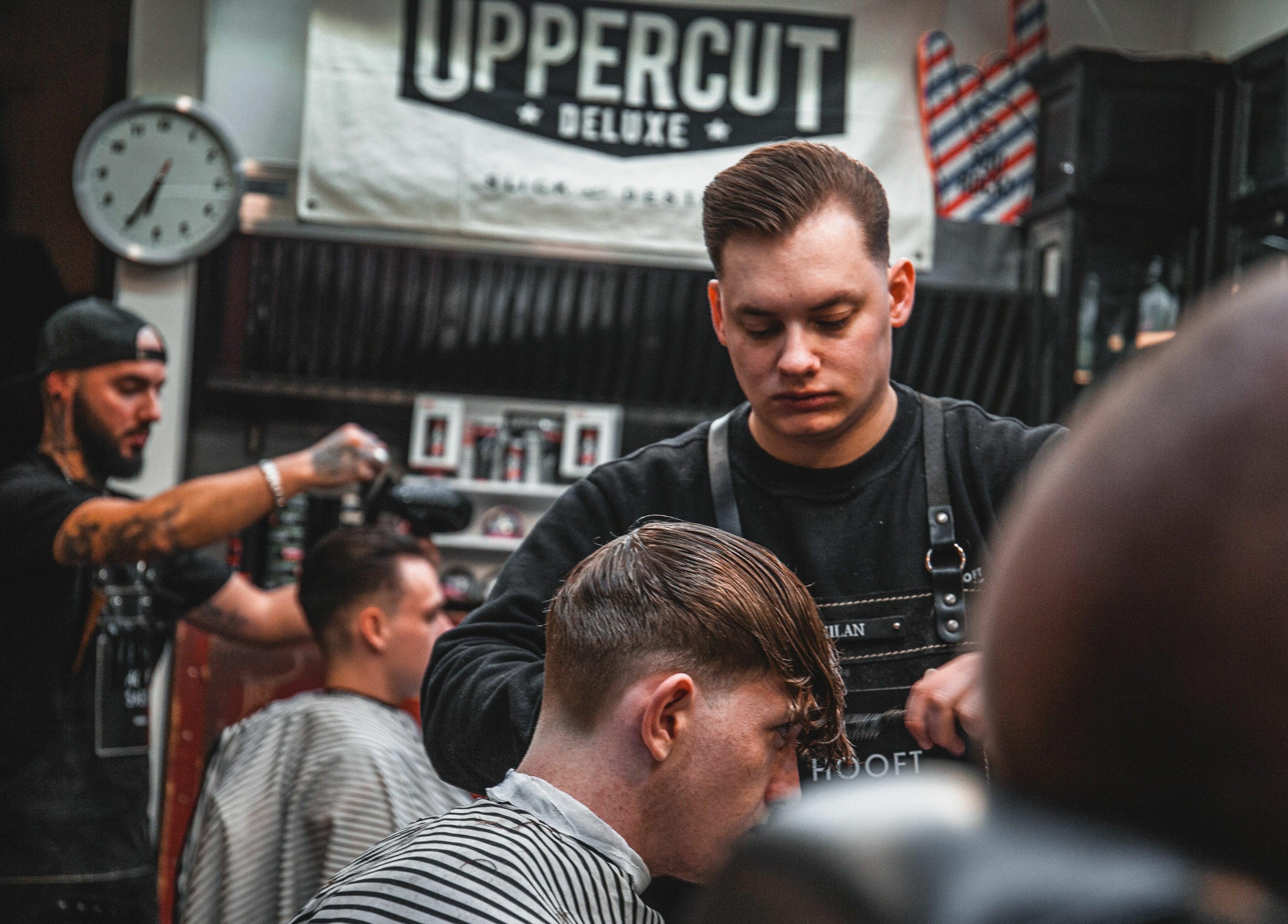 Kapsters knippen haar bij Hooftsaeck Barbershop in Harderwijk, Gelderland, NL voor een stijlvolle afwerking.